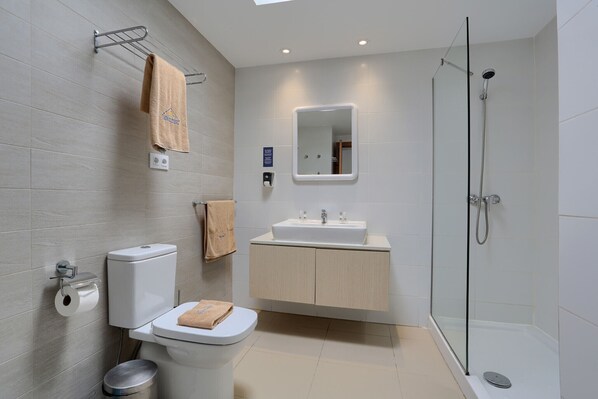 A modern bathroom with a toilet, sink, and shower.