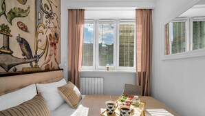 Quarto aconchegante com uma cama, uma mesinha de cabeceira com uma bandeja de itens de café da manhã e uma janela com persianas.