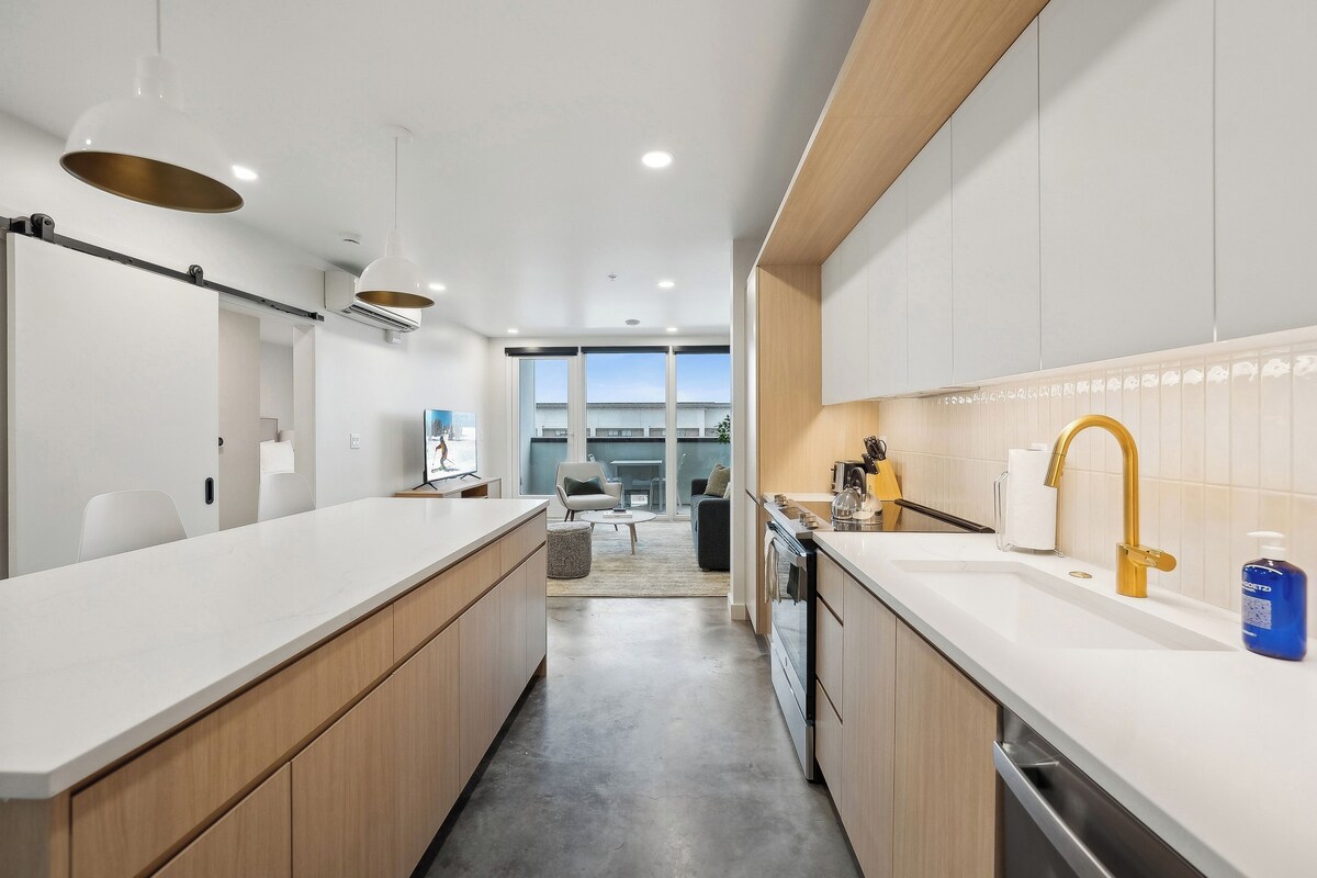Una cocina moderna con una isla central, armarios blancos y vistas al exterior.