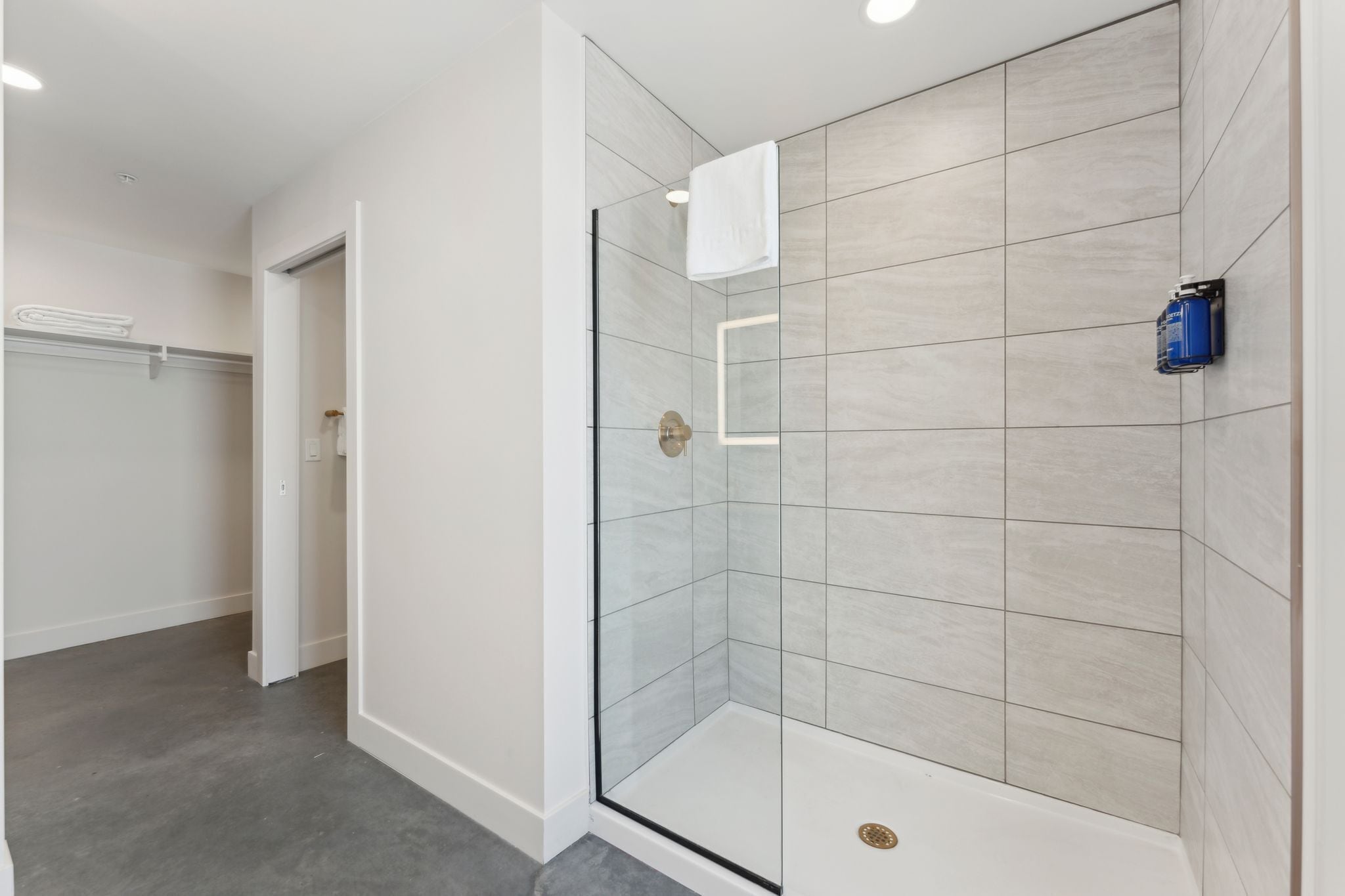 A modern bathroom with a glass-enclosed shower, tiled walls, and a white door.