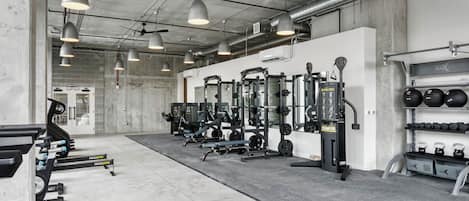 Une salle de sport équipée de matériel de musculation, de tapis de course et d’haltères.