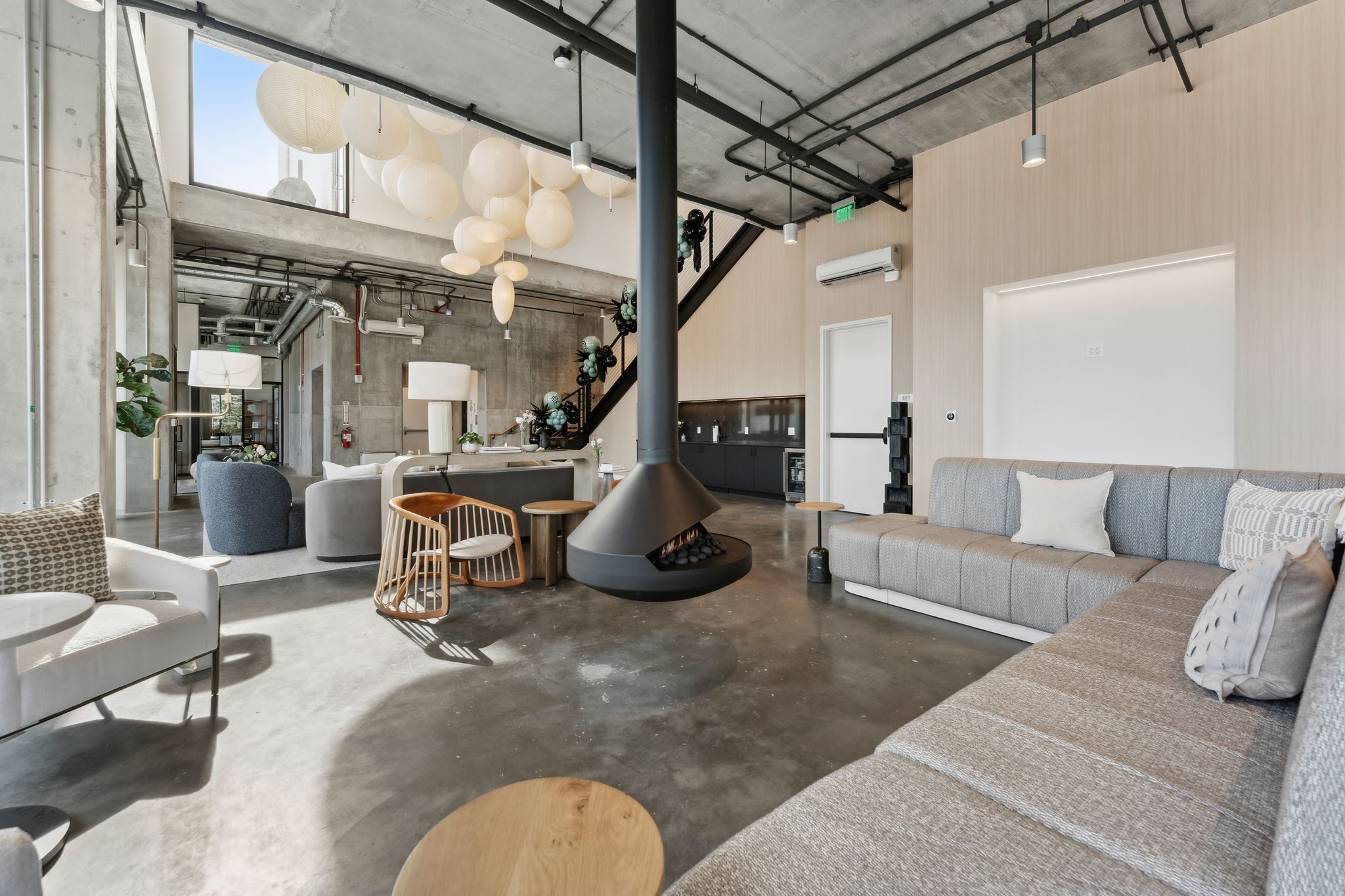 A modern interior with a large seating area, a fireplace, and a staircase.