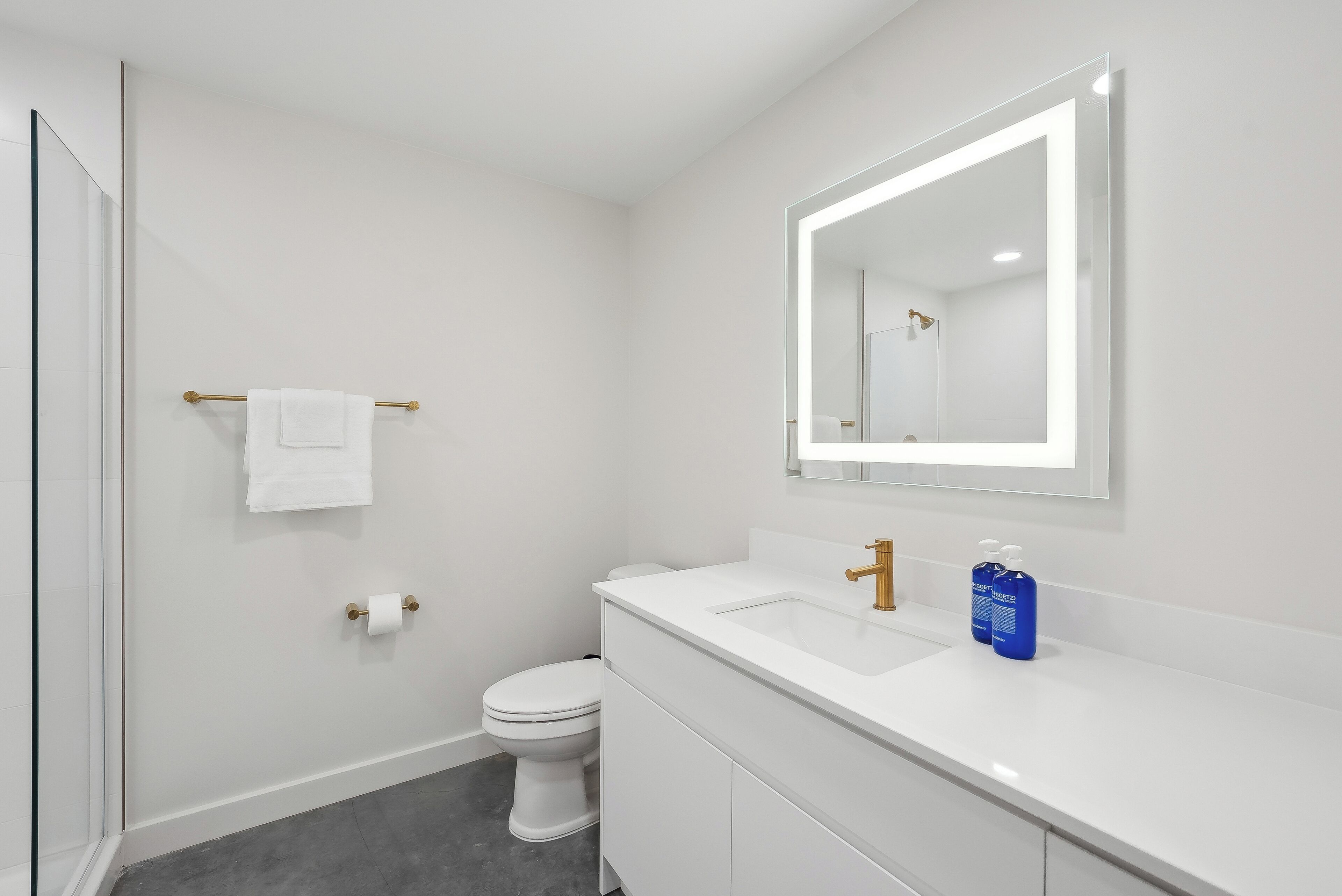 Une salle de bain moderne avec un lavabo blanc, un miroir et des toilettes.