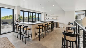 A modern kitchen with a bar area, large windows, and a view of the outdoors. -  Placemakr Salt Lake City Downtown, Apartments by Hilton (Salt Lake City)