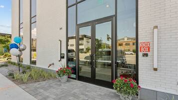 A modern building with a glass entrance, a Knox Box sign, and potted plants on the sidewalk.