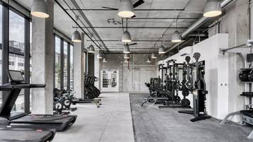 Une salle de sport équipée de tapis de course, de vélos elliptiques et de matériel de musculation.