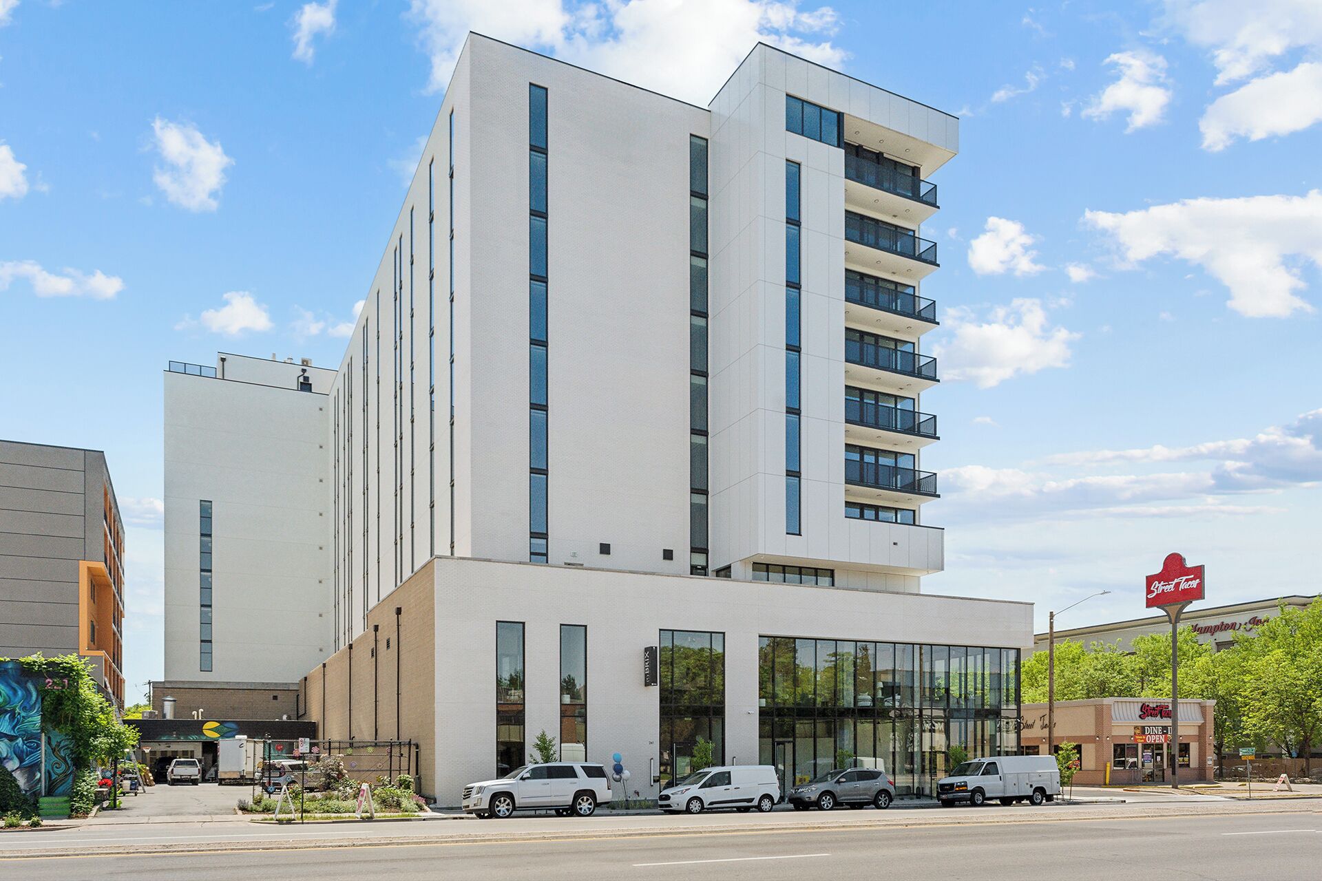 Un hotel moderno con fachada blanca, varios pisos y entrada de vidrio.