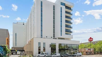 Un hotel moderno con fachada blanca, varios pisos y entrada de vidrio.