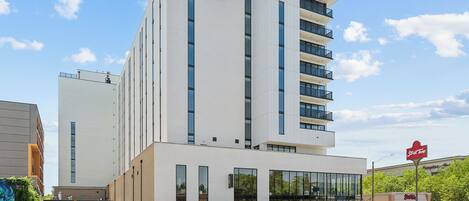 Un hotel moderno con fachada blanca, varios pisos y entrada de vidrio.