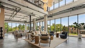 A spacious, modern interior with large windows, a high ceiling, and a mix of seating areas. -  Placemakr Salt Lake City Downtown, Apartments by Hilton (Salt Lake City)