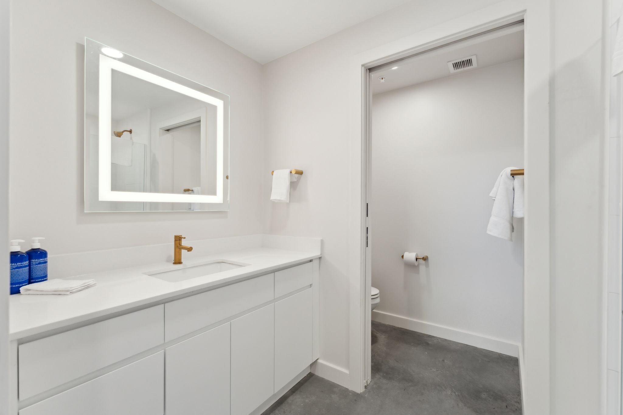 A modern bathroom with a white vanity, a large mirror, and a shower area.