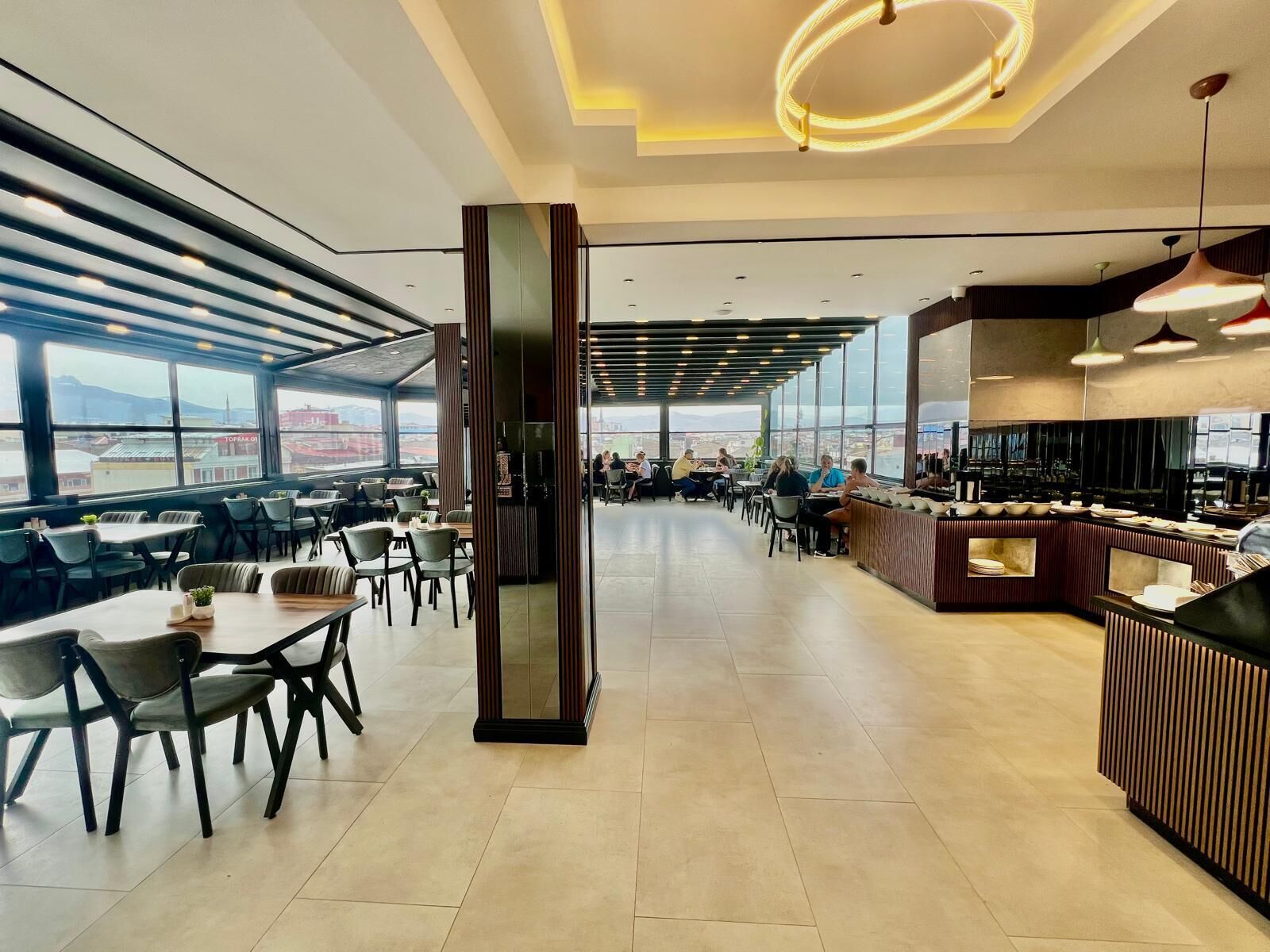 A modern restaurant with a high ceiling, large windows, and a central serving area.