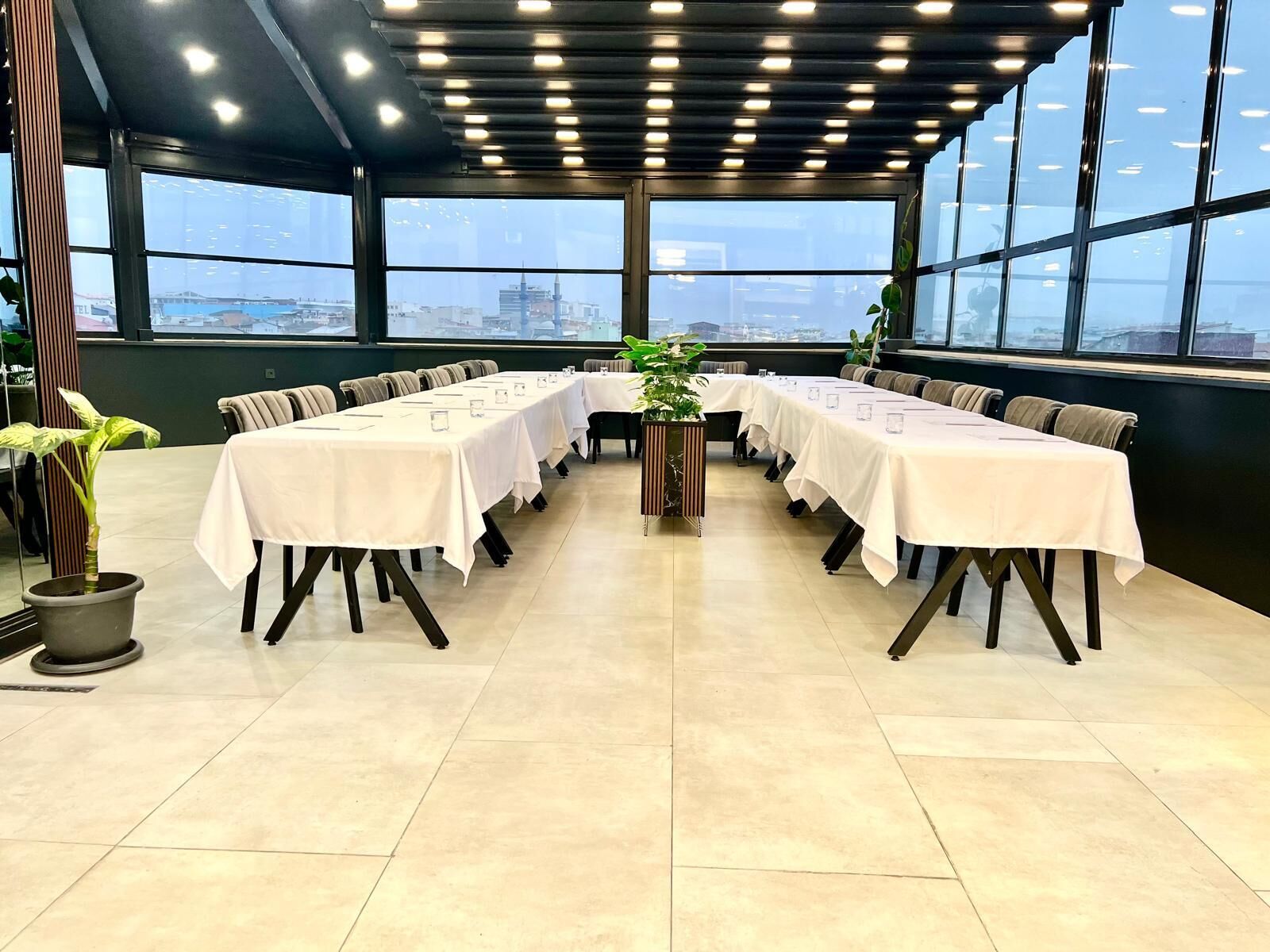 Een vergaderzaal met een lange tafel, stoelen en potplanten.
