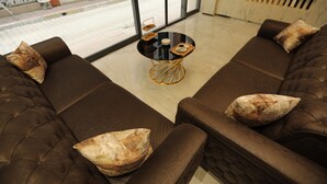 A modern living room with brown sofas and a glass coffee table. - KARAKOÇ HOTEL  (Van)