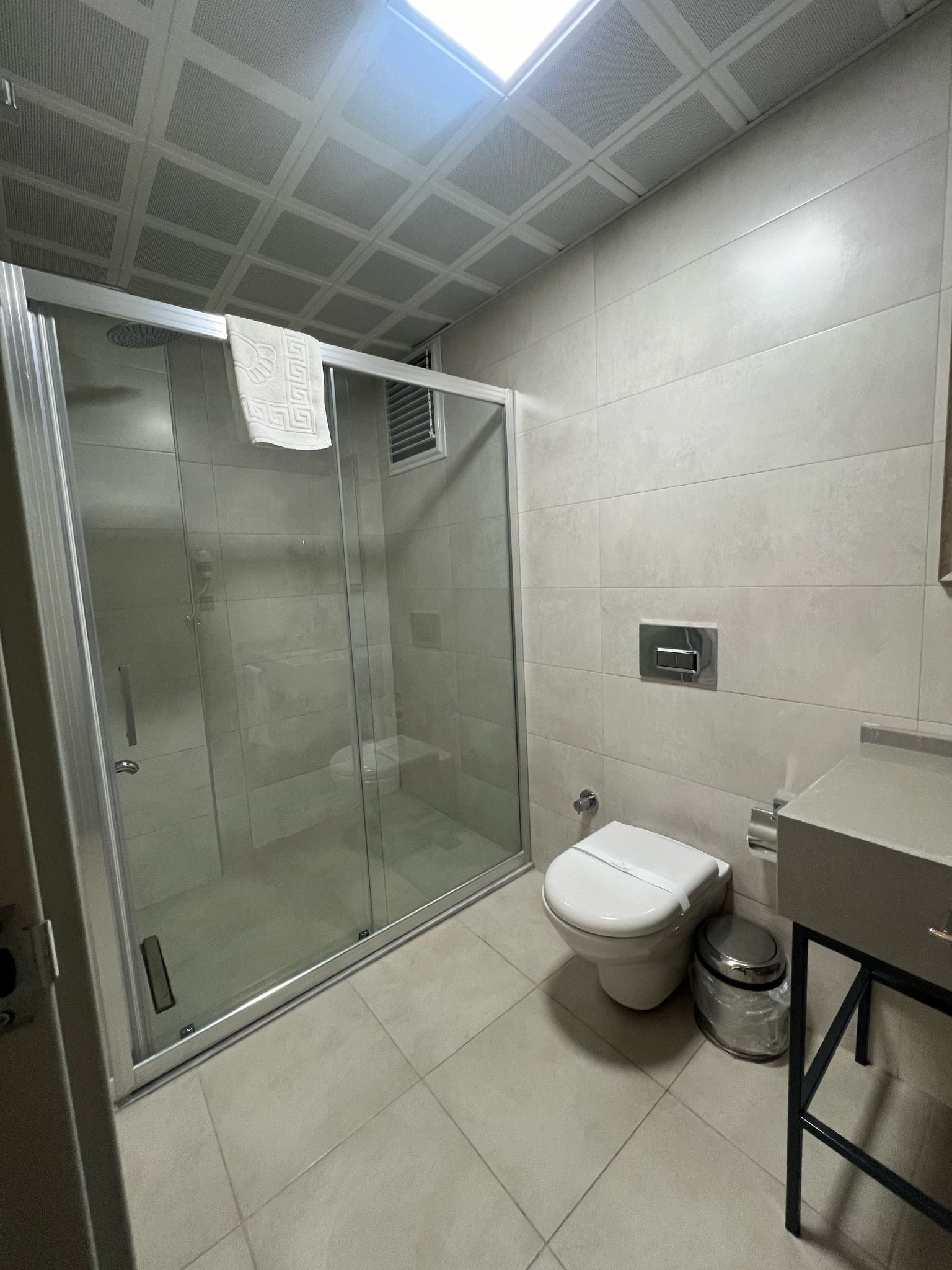 Un baño moderno con cabina de ducha de vidrio, inodoro y lavamanos.