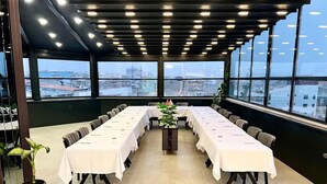 A conference room with a long table, chairs, and large windows offering a city view. - KARAKOÇ HOTEL  (Van)