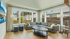 A spacious living room with a sectional sofa, a round coffee table, and a view of the backyard through large windows. - "BRAND NEW"  Littoral Lookout at Pacific Beach (Pacific Beach)