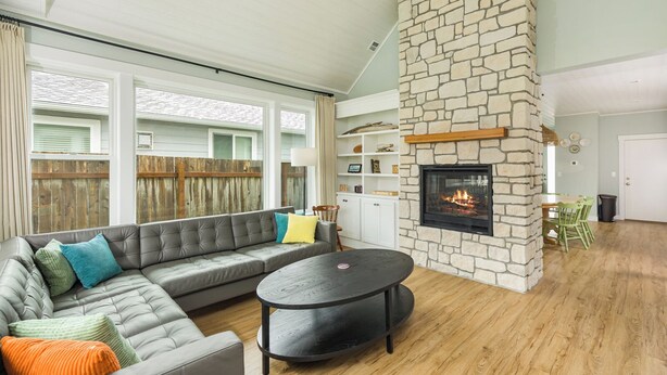 A living room with a stone fireplace, a gray sectional sofa, and a round coffee table. - "BRAND NEW"  Littoral Lookout at Pacific Beach (Pacific Beach)