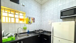 A compact kitchen with white tiled walls, a black countertop, and a white refrigerator. - 1BEDROOM FLAT at UTAKO ABUJA. 24hrs LIGHT, WIFI & KITCHEN (Abuja)