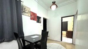 A dining area with a black table and chairs, a white tiled floor, and a ceiling light fixture. - 1BEDROOM FLAT at UTAKO ABUJA. 24hrs LIGHT, WIFI & KITCHEN (Abuja)