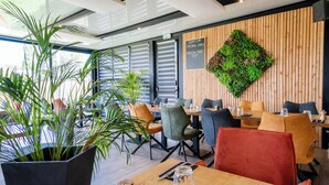 A modern restaurant interior with wooden panel walls, green plants, and a variety of seating options. - Domaine du Vieux Porche (Mignaloux-Beauvoir)