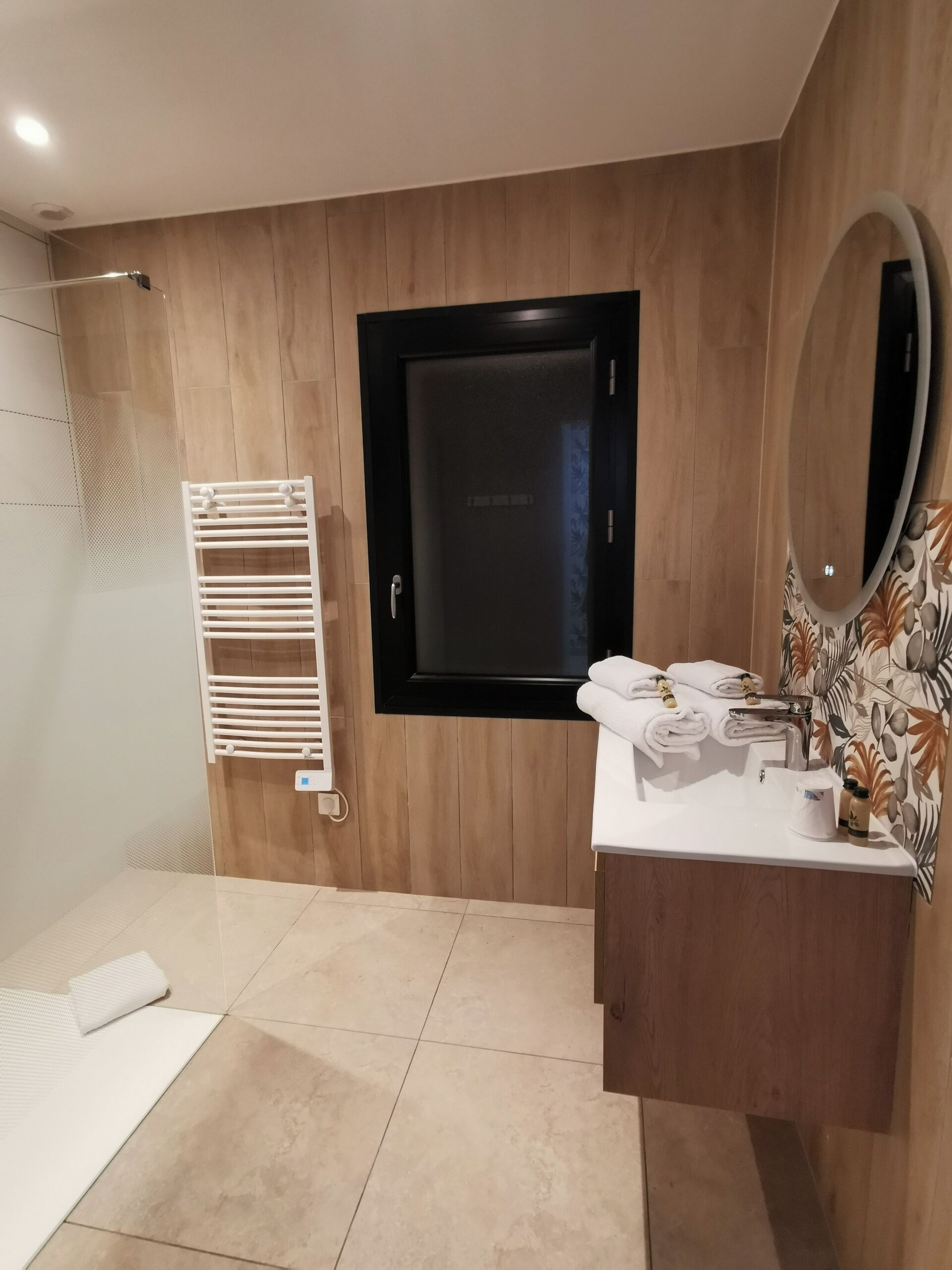 Un baño moderno con tocador de madera, un espejo grande y un perchero para toallas.