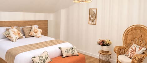 Un dormitorio con una cama, una silla, una mesita y una lámpara colgante.