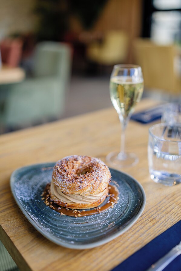A dessert on a plate with a glass of champagne and a water glass on a wooden table.
