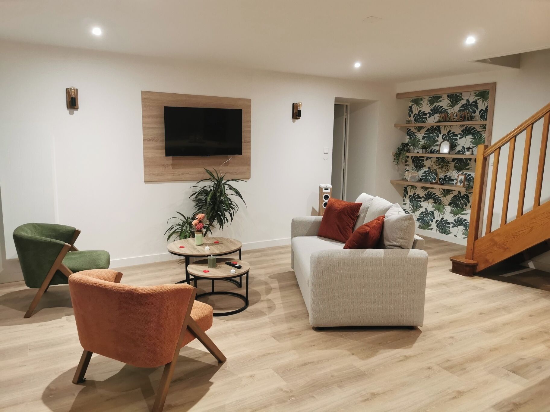 Een moderne woonkamer met een grijze bank, een groene fauteuil en een ronde salontafel.