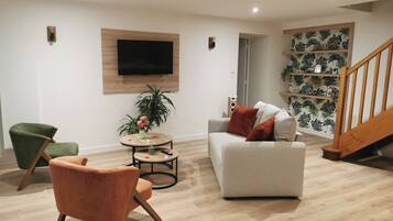 Een moderne woonkamer met een grijze bank, een groene fauteuil en een ronde salontafel.