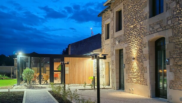 A modern building with stone walls and a gravel pathway leading to a wooden deck. - Domaine du Vieux Porche (Mignaloux-Beauvoir)