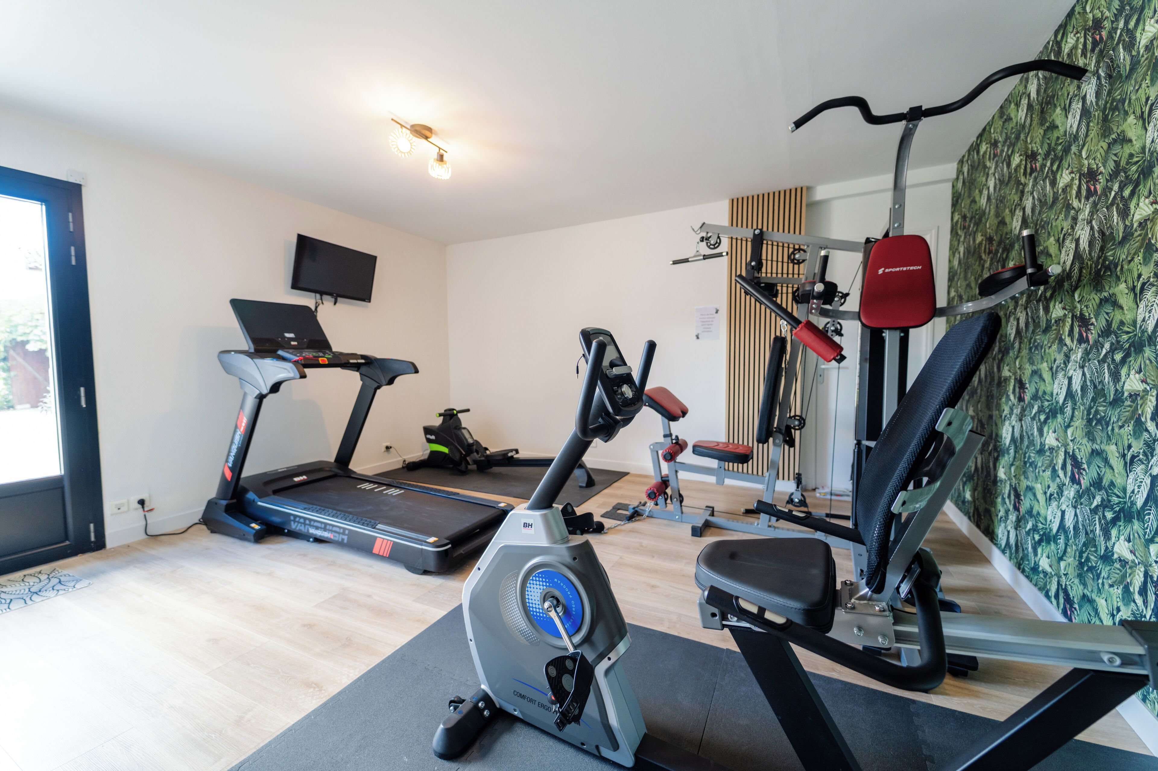 Un gimnasio en casa con cinta de correr, bicicleta estática y máquina elíptica.