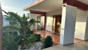 Ein modernes Haus mit überdachter Terrasse, einem gepflegten Garten und einer Tür zum Innenbereich.