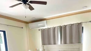 Ein Schlafzimmer mit einem Bett, einem weißen Sofa, einem Nachttisch und einem Deckenventilator.