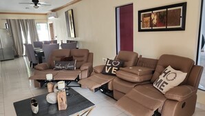 Ein modernes Wohnzimmer mit einem Ecksofa, einem Couchtisch und einem Essbereich im Hintergrund.