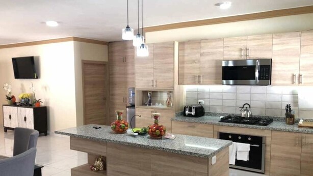 Eine moderne Küche mit Kochinsel, Edelstahlgeräten und Holzschränken.