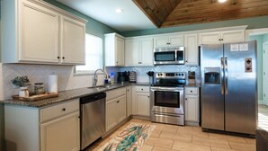 A kitchen with white cabinets, stainless steel appliances, a wooden ceiling, and a tiled backsplash. - Angler’s Paradise! Amazing fishing w/ in minutes! 3 bed,sleeps 7 ppl, 2 bath. (Hackberry)