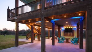 A wooden deck with outdoor seating and a staircase leading to a balcony. - Angler’s Paradise! Amazing fishing w/ in minutes! 3 bed,sleeps 7 ppl, 2 bath. (Hackberry)