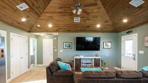A spacious living room with a wooden ceiling, a large flat-screen TV, and a sofa set. - Angler’s Paradise! Amazing fishing w/ in minutes! 3 bed,sleeps 7 ppl, 2 bath. (Hackberry)