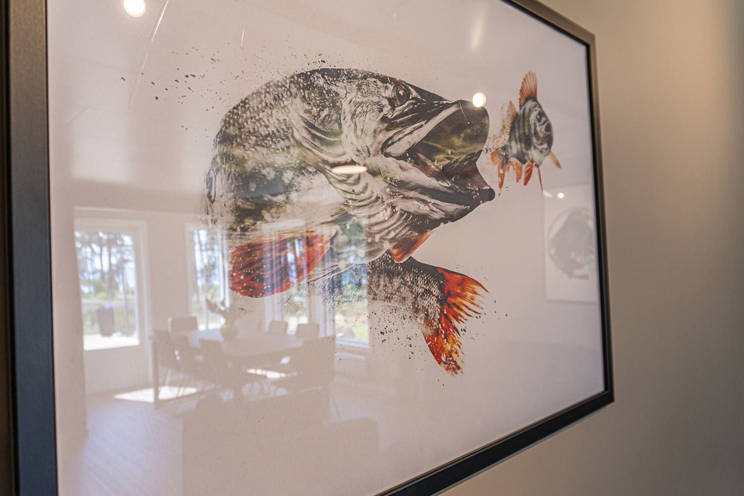 A framed artwork of a fish with a red tail, displayed on a wall.
