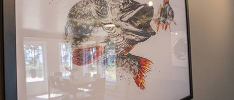 A framed artwork of a fish with a red tail, displayed on a wall.