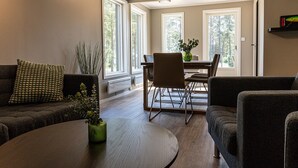A modern living room with a sofa, a coffee table, and a dining area with a table and chairs. - Perchlodge (Monsteras)