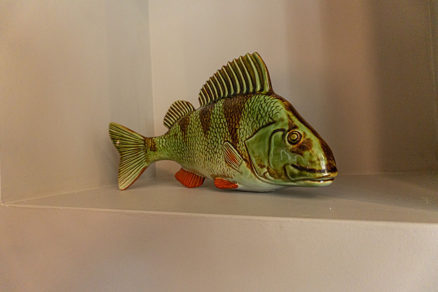 A ceramic fish sculpture on a shelf.