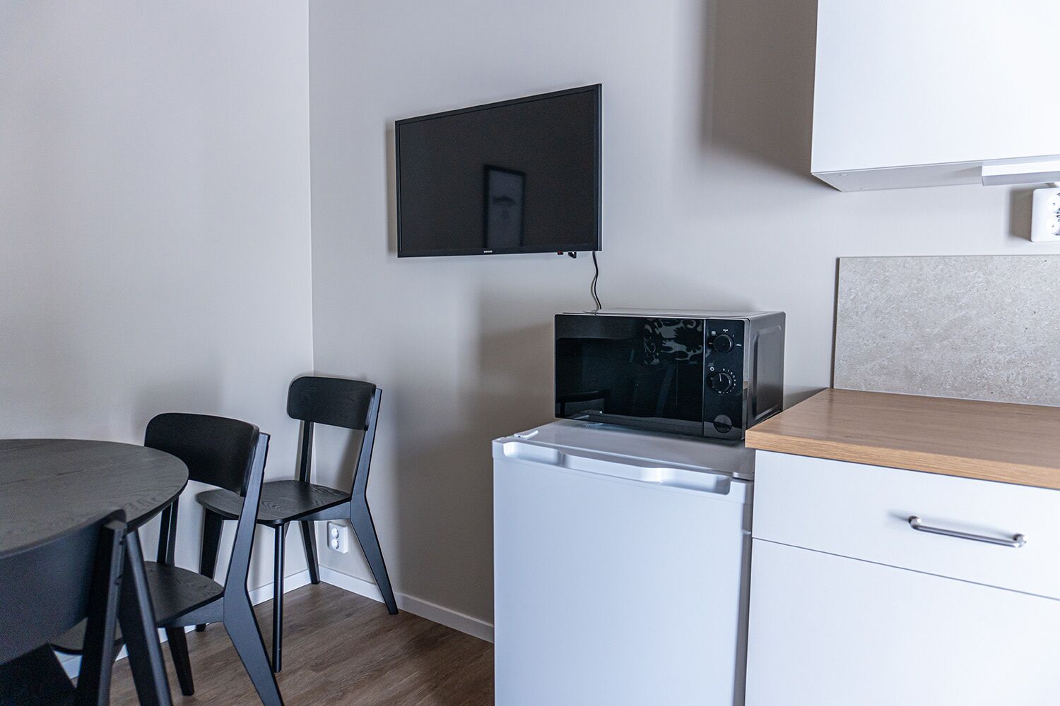 Une petite cuisine équipée comprenant un four à micro-ondes, un petit réfrigérateur, un plan de travail en bois et un coin repas avec une table et deux chaises.