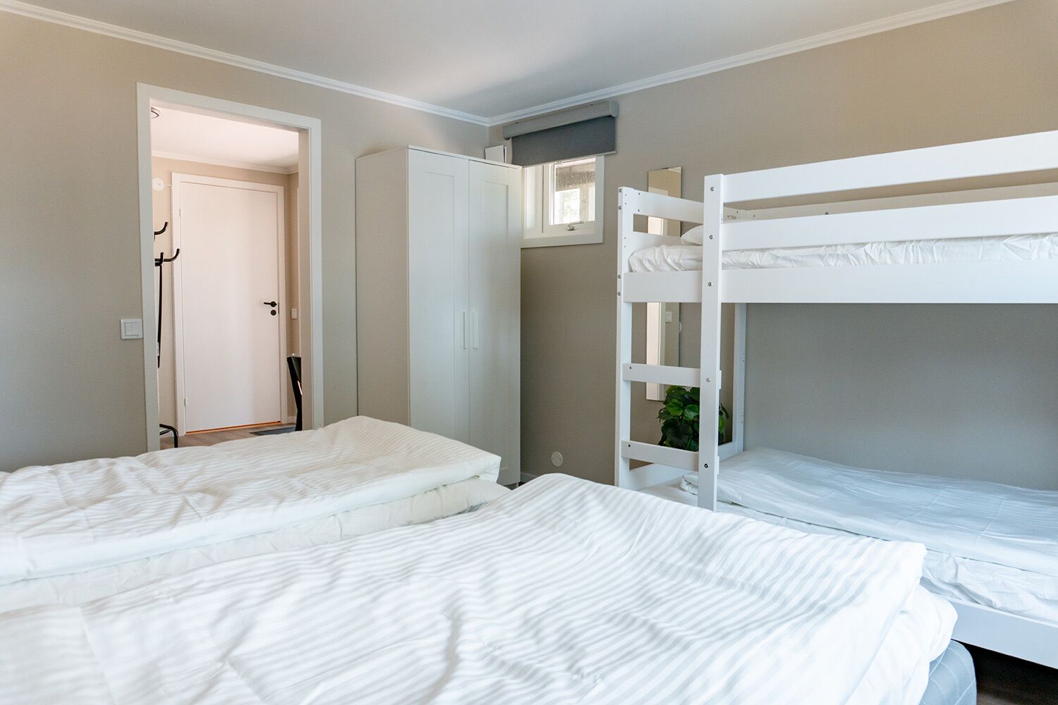 A room with two beds, a wardrobe, and a window.