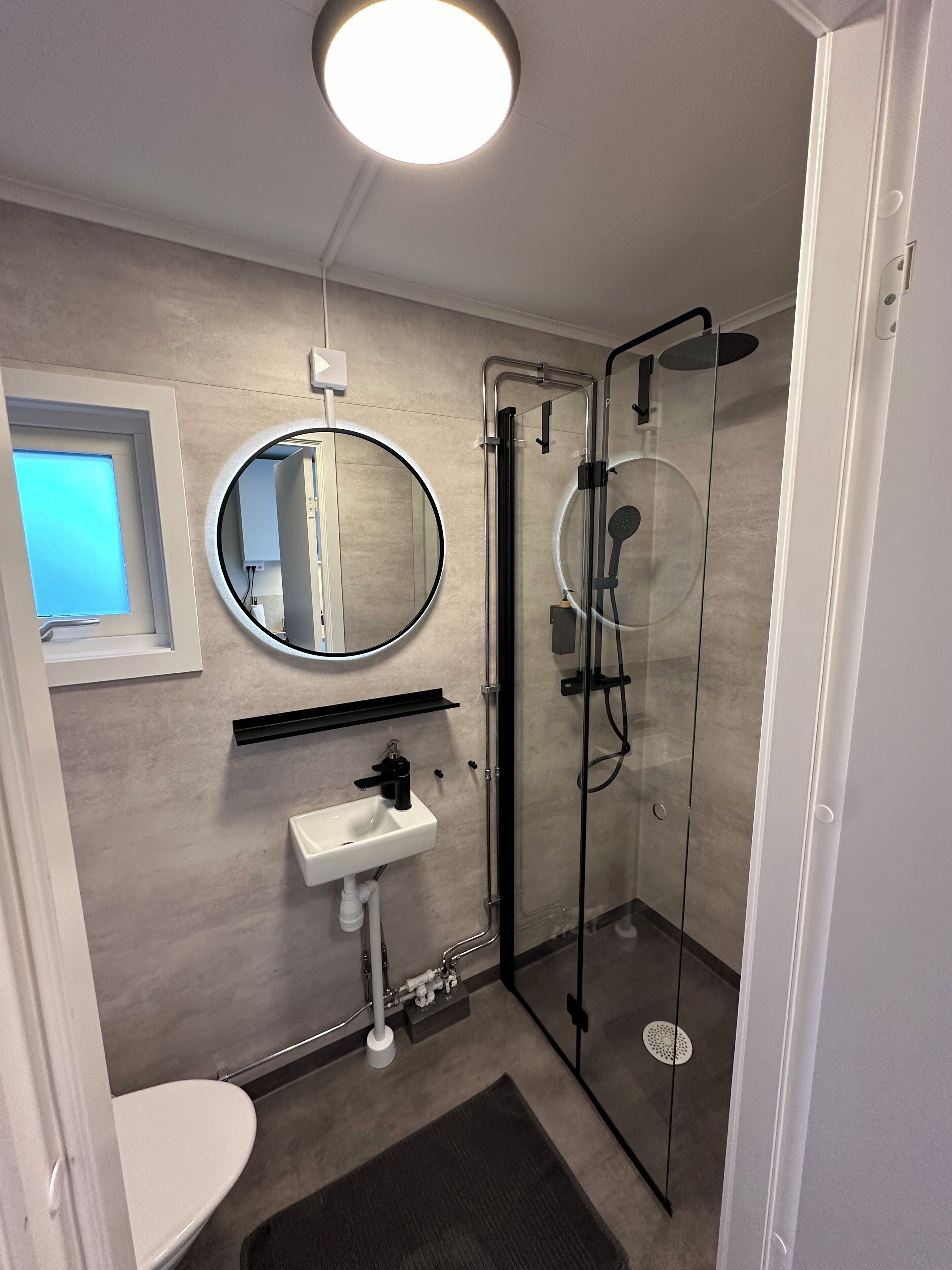 A modern bathroom with a toilet, sink, and glass-enclosed shower.