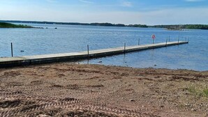 A calm lake with a concrete dock extending into the water, surrounded by a barren landscape. - Perchlodge (Monsteras)