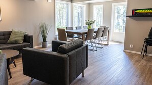 A modern living room with a sofa, a coffee table, and a dining area with a table and chairs. - Perchlodge (Monsteras)