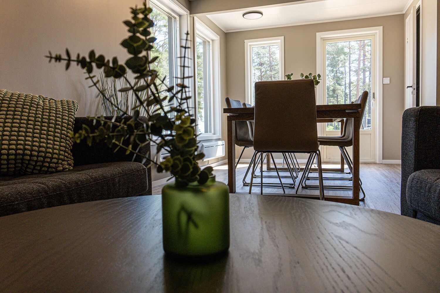 Una zona de comedor con una mesa de madera, sillas y un florero con plantas.