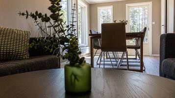 Una zona de comedor con una mesa de madera, sillas y un florero con plantas.